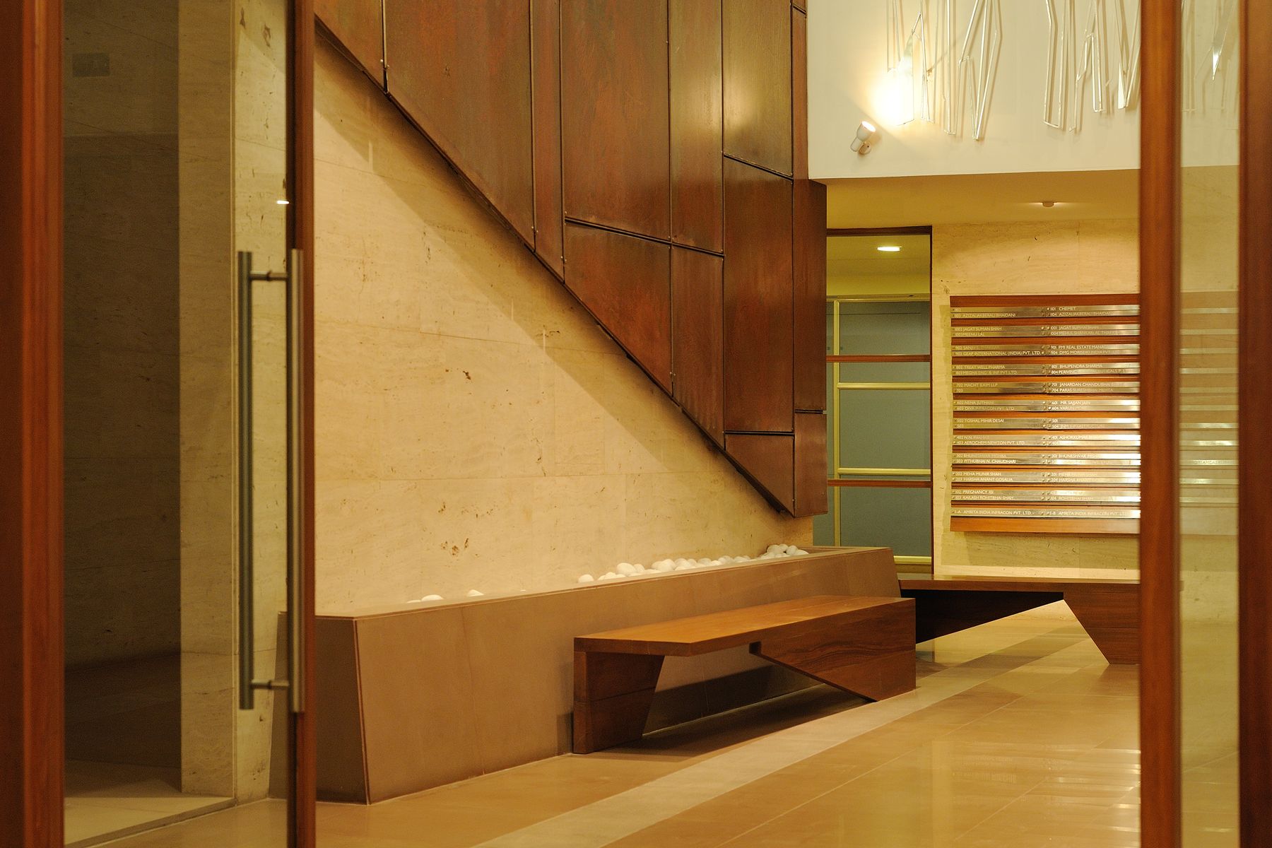 office foyer design, interior design, travertine cladding, metal shavings, wooden furniture, Indian architects, rusted steel